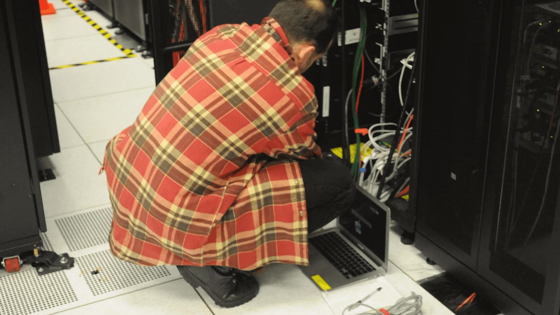 A technician working beside a server rack, representing secure business messaging infrastructure and operator trust.